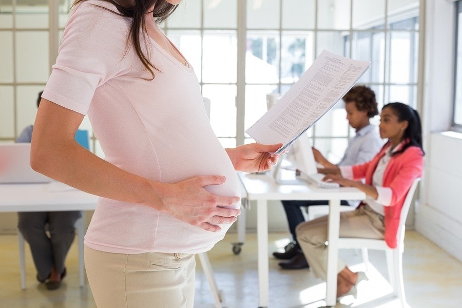 Pregnant-office-worker-touches-belly-66166213