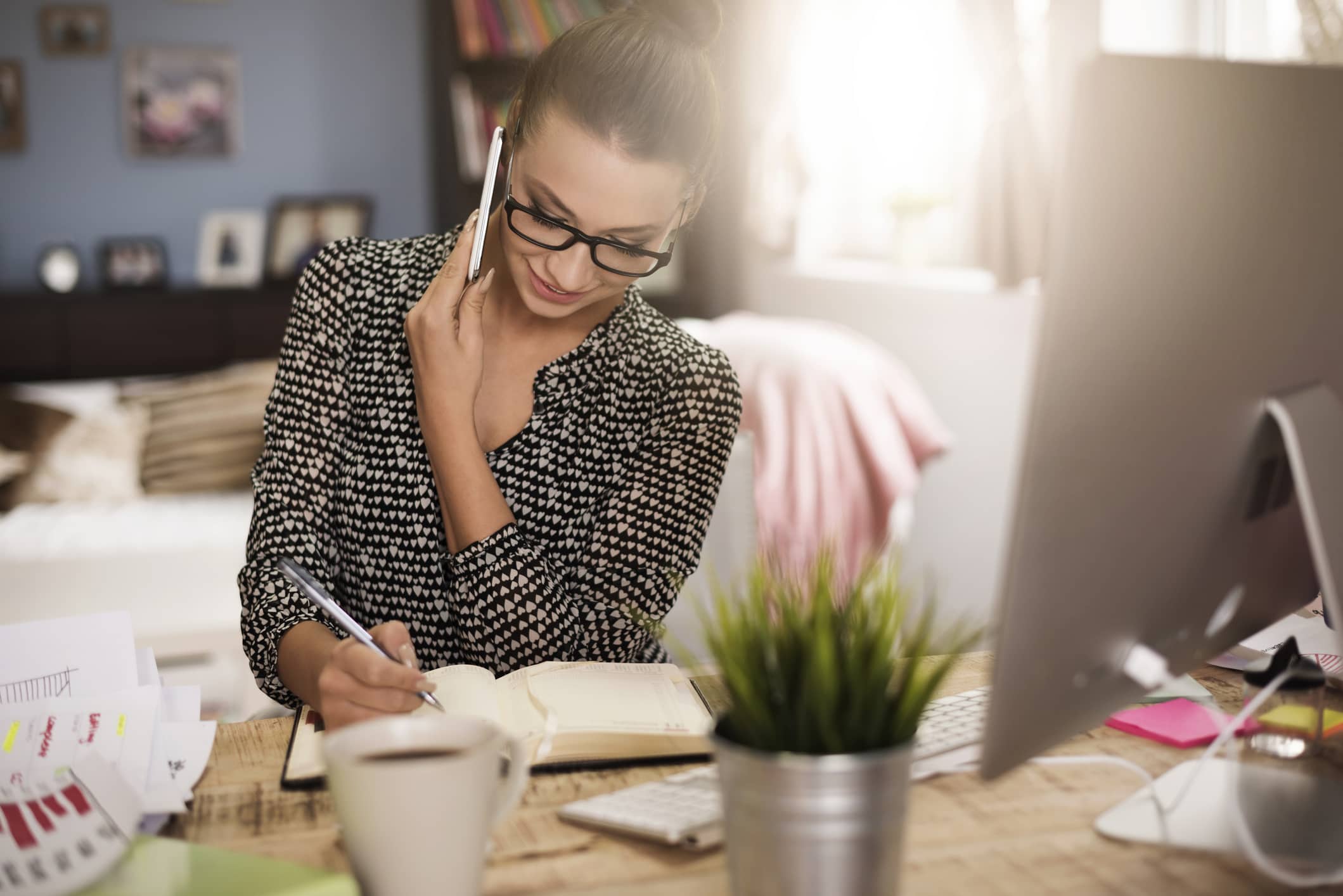 Blonde woman in glasses on the phone working in home office