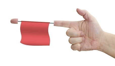 Finger gun with a red flag dangling from index finger.