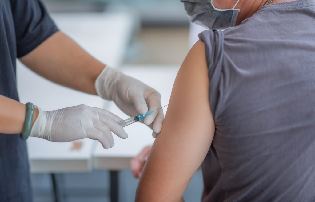 doctor injects healthcare worker with vaccine